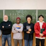 A-diverse-group-of-students-and-a-teacher-smiling-in-front-of-a-chalkboard-filled-with-formulas.-2025-05-01T095327.484-0400-pexels-photo-8197537