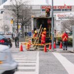 Full-body-of-workers-in-red-uniforms-and-yellow-helmets-carrying-wooden-ladder-in-street-near-automobile-road-2025-05-01T155324.240-0400-pexels-photo-4254892