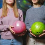 Two-women-holding-pink-and-green-bowling-balls-inside-a-bowling-alley.-2025-09-28T063435.940-0400-pexels-photo-5952897